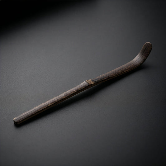 Dark bamboo chashaku matcha scoop on black background 